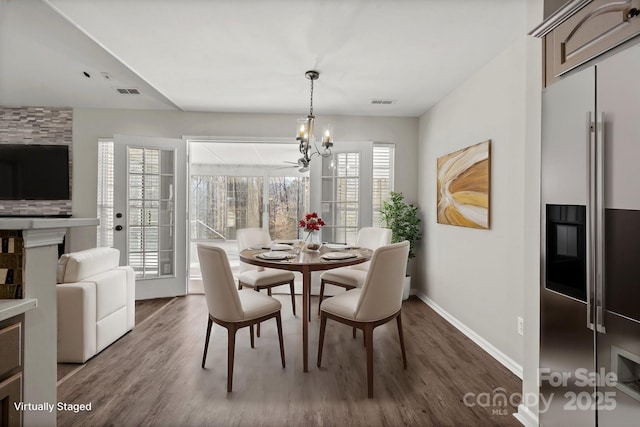 dining area featuring dark wood-type flooring, a notable chandelier, baseboards, and visible vents