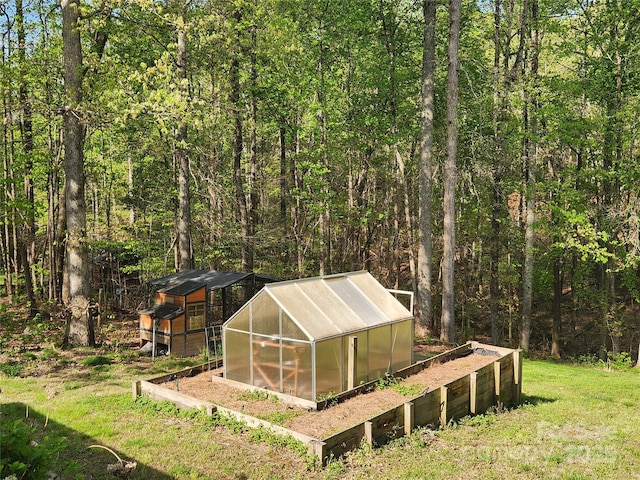 view of greenhouse featuring a yard and a view of trees