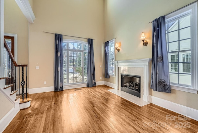 foyer entrance with hardwood / wood-style flooring, a high ceiling, and a high end fireplace