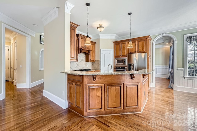 kitchen featuring hanging light fixtures, light stone counters, ornamental molding, decorative backsplash, and stainless steel appliances