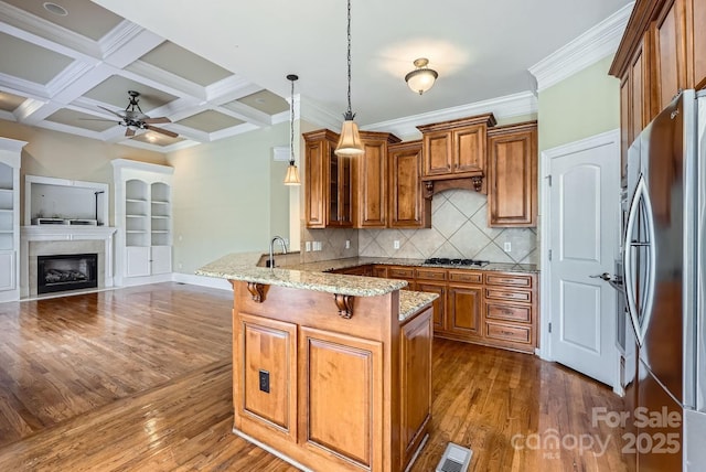 kitchen featuring kitchen peninsula, hanging light fixtures, coffered ceiling, a breakfast bar area, and stainless steel refrigerator