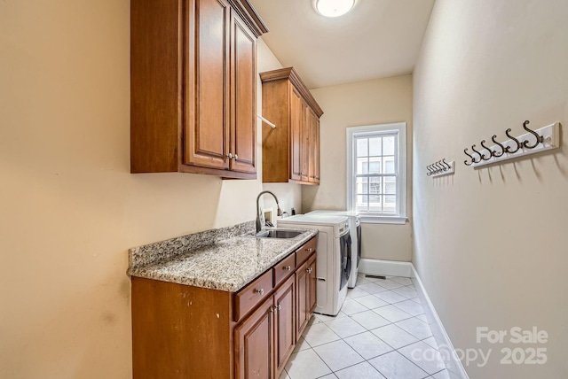 washroom with sink, cabinets, washing machine and dryer, and light tile patterned floors