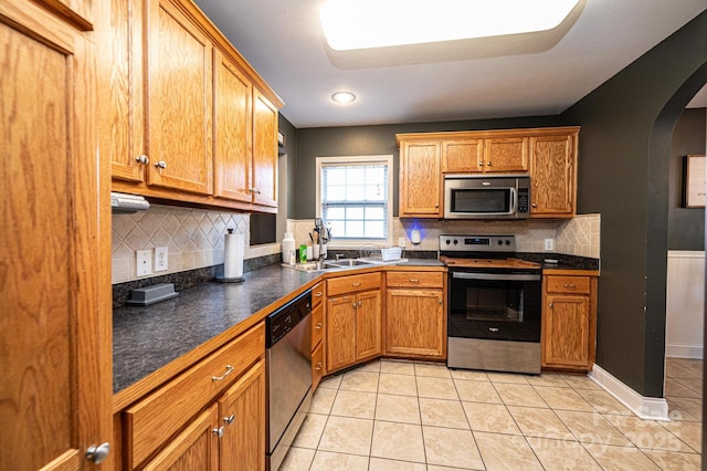 kitchen with sink, stainless steel appliances, light tile patterned floors, and tasteful backsplash