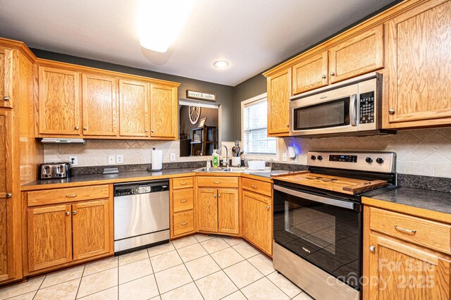 kitchen with sink, light tile patterned floors, appliances with stainless steel finishes, and tasteful backsplash