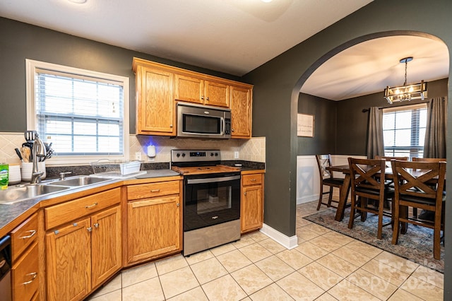 kitchen featuring light tile patterned flooring, plenty of natural light, tasteful backsplash, and stainless steel appliances