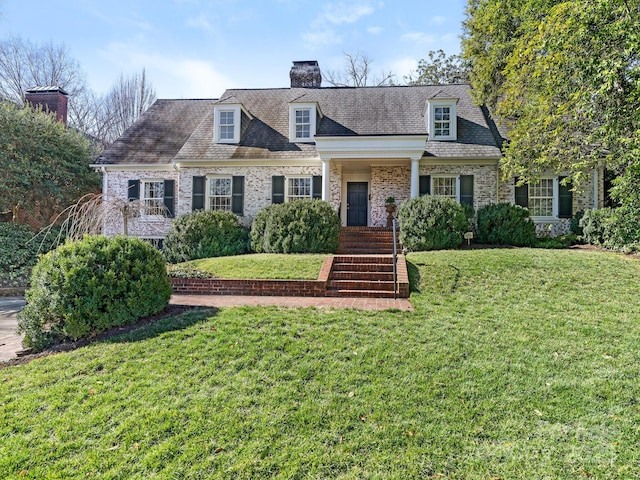 new england style home with a chimney and a front yard