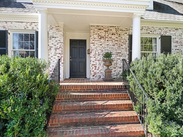 property entrance with brick siding and a shingled roof