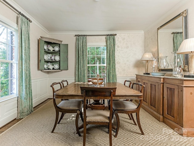 dining space with a wainscoted wall, a decorative wall, and crown molding