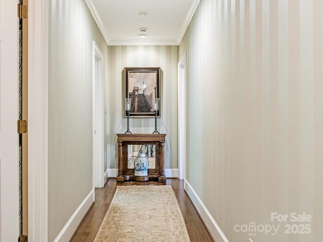 hall with dark wood-style floors, ornamental molding, and baseboards