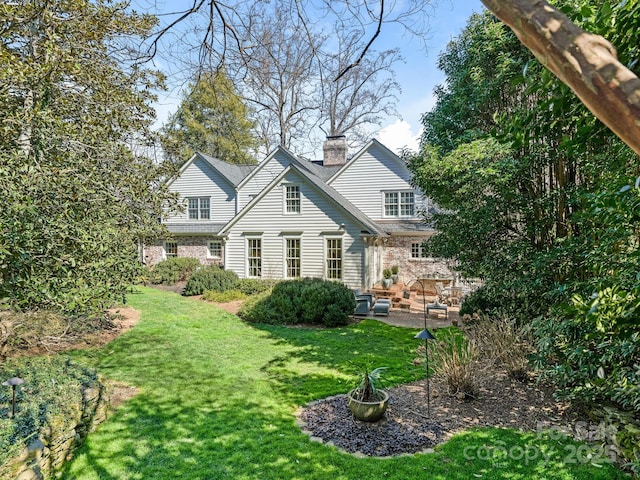 rear view of property with a yard, a chimney, and a patio area