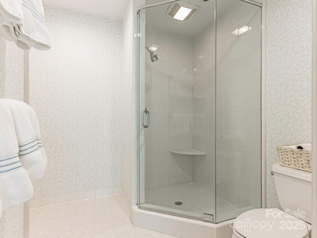 bathroom with a shower stall, tile patterned flooring, toilet, and wallpapered walls