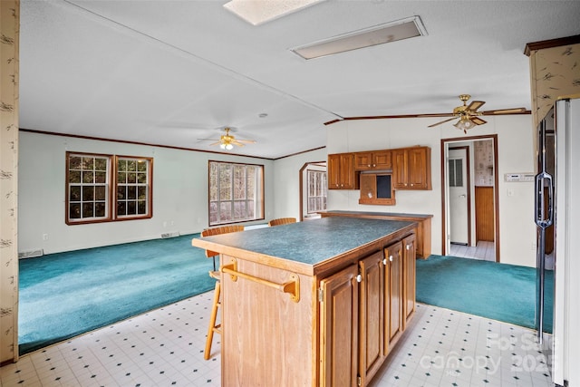 kitchen with a breakfast bar area, refrigerator, vaulted ceiling, a kitchen island, and light colored carpet