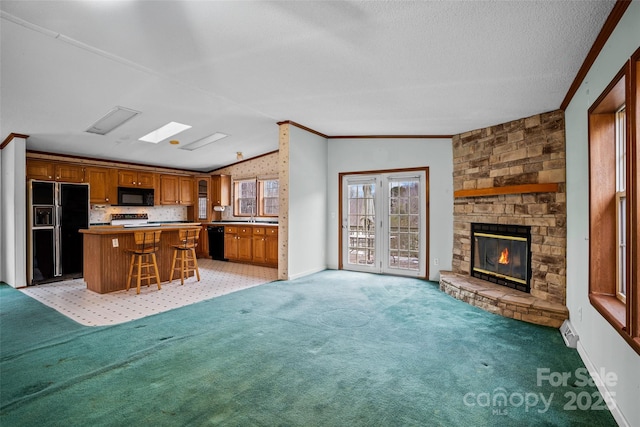 unfurnished living room featuring a stone fireplace, lofted ceiling, ornamental molding, light colored carpet, and a textured ceiling