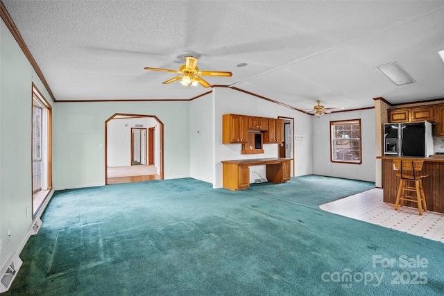 carpeted living room featuring crown molding, ceiling fan, vaulted ceiling, and a textured ceiling