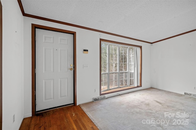 foyer entrance with crown molding, dark hardwood / wood-style floors, and a textured ceiling