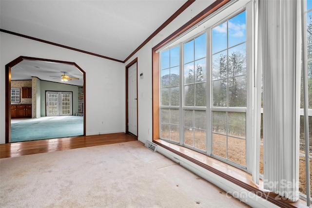 carpeted empty room featuring vaulted ceiling, ornamental molding, and ceiling fan