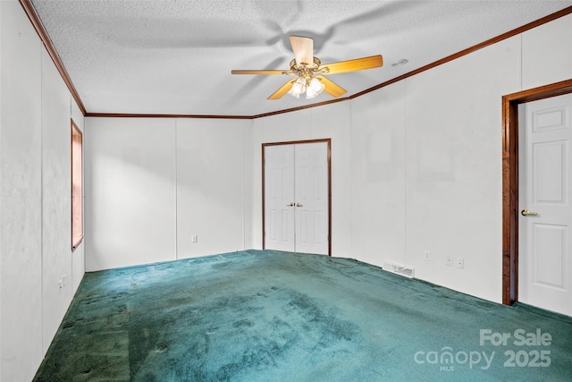 carpeted spare room with ceiling fan, ornamental molding, and a textured ceiling