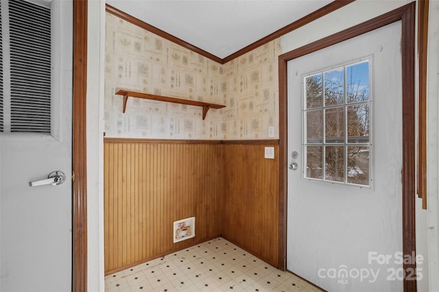 doorway to outside with wood walls, ornamental molding, and plenty of natural light