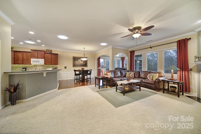 living room with ceiling fan, ornamental molding, a healthy amount of sunlight, and carpet