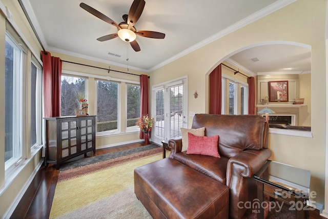 living area featuring hardwood / wood-style floors, ornamental molding, and ceiling fan