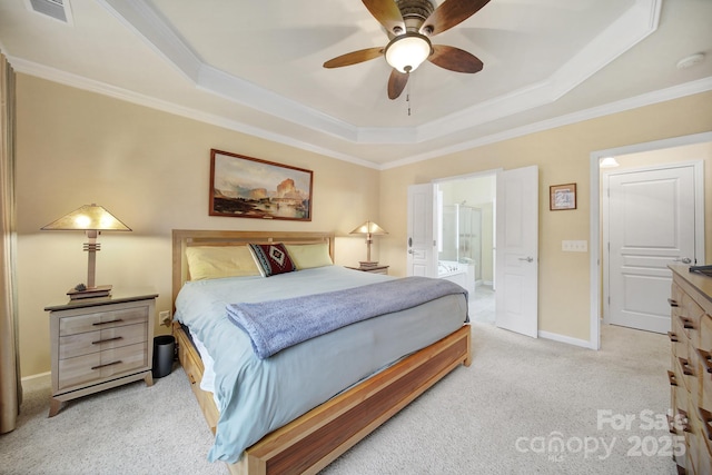 carpeted bedroom with connected bathroom, a tray ceiling, ornamental molding, and ceiling fan