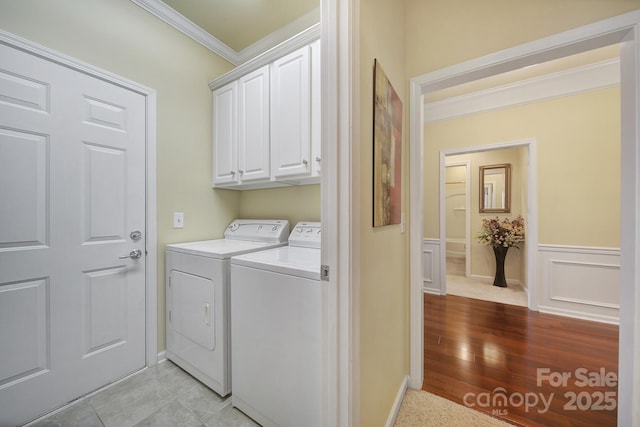 clothes washing area with cabinets, independent washer and dryer, and crown molding