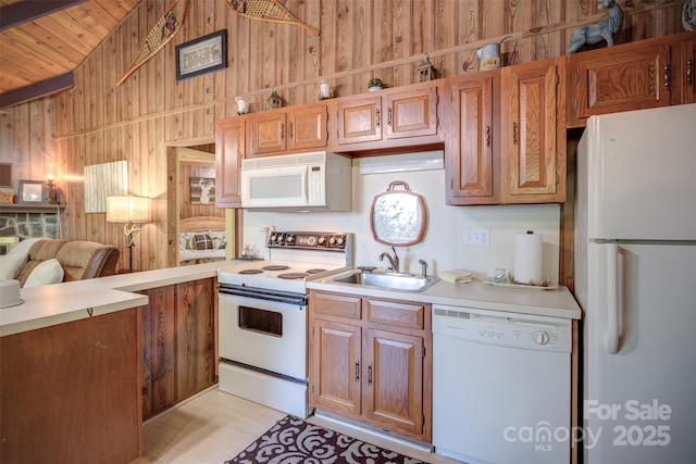 kitchen with wood walls, sink, and white appliances