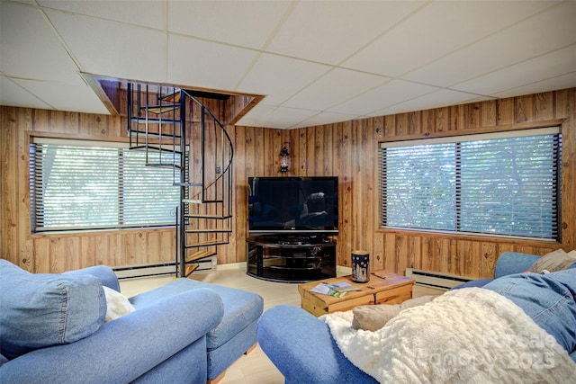 living room with a paneled ceiling, wood walls, and a baseboard radiator