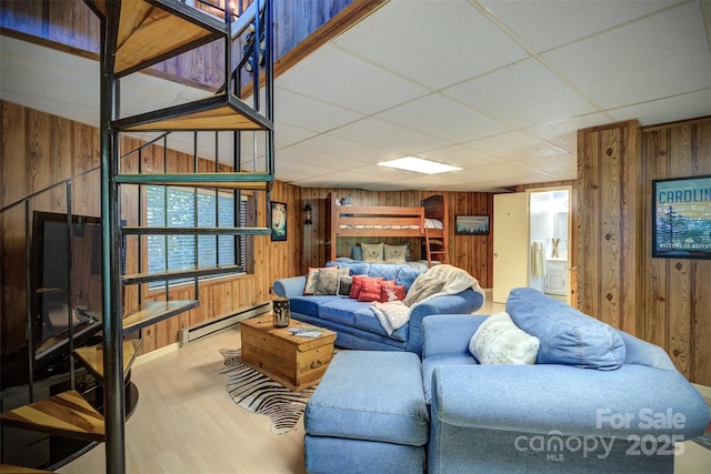 living room with a baseboard radiator, a paneled ceiling, and wooden walls