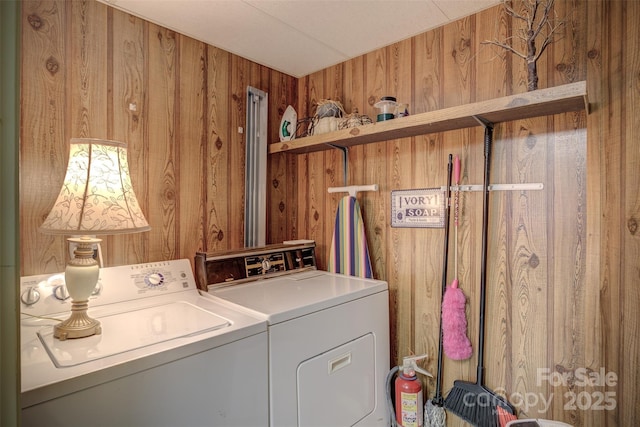 laundry area with wooden walls and washing machine and clothes dryer