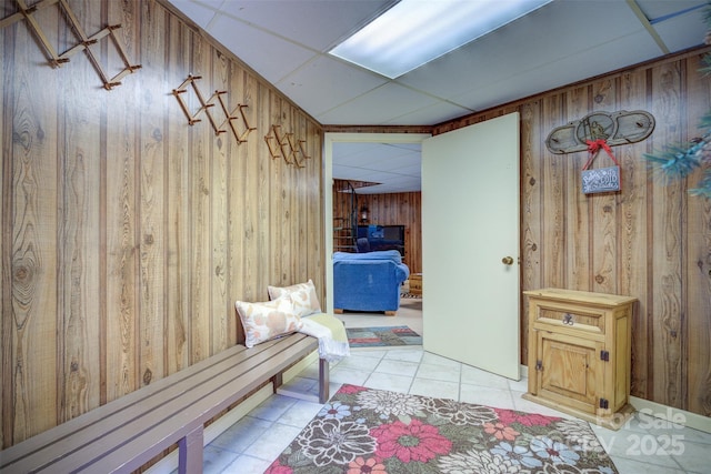 mudroom with light tile patterned floors, a drop ceiling, and wooden walls