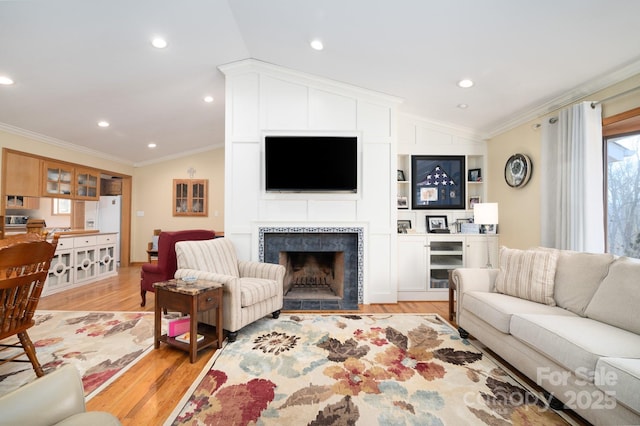 living room featuring lofted ceiling, a fireplace, ornamental molding, and light hardwood / wood-style floors