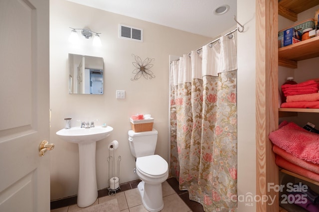 bathroom featuring walk in shower, sink, toilet, and tile patterned flooring