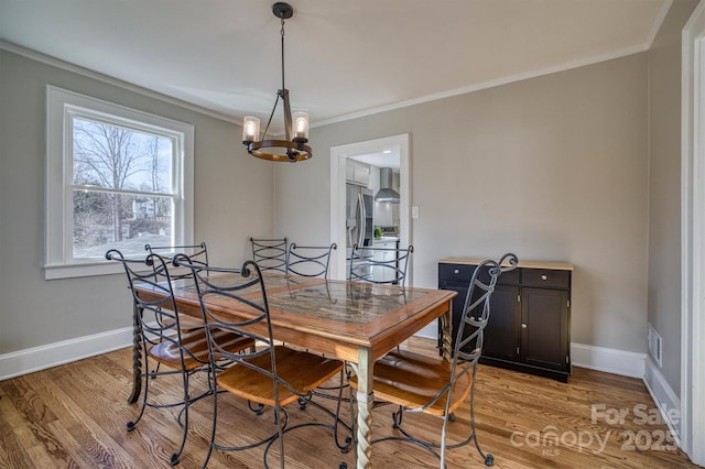 dining room with ornamental molding, an inviting chandelier, and light wood-type flooring