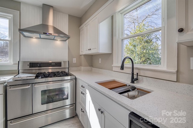 kitchen featuring white cabinetry, sink, range with two ovens, light stone countertops, and wall chimney exhaust hood