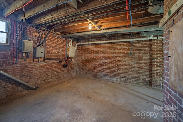 basement featuring electric panel, water heater, and brick wall