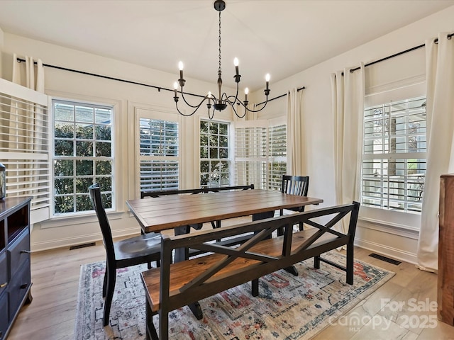 dining room with a wealth of natural light, light hardwood / wood-style flooring, and a chandelier