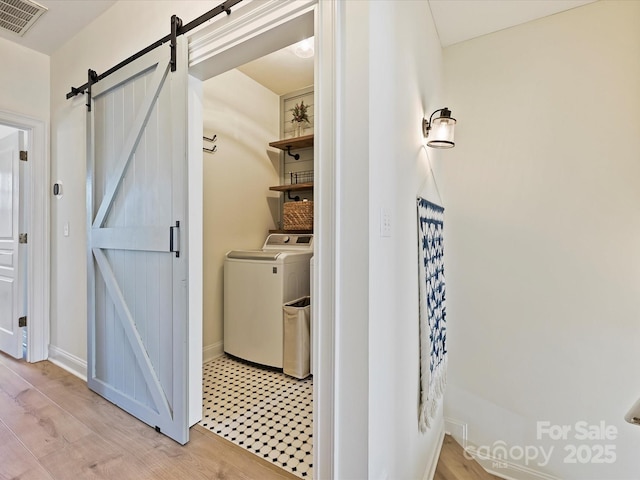 laundry area featuring light hardwood / wood-style floors, a barn door, and washer / clothes dryer