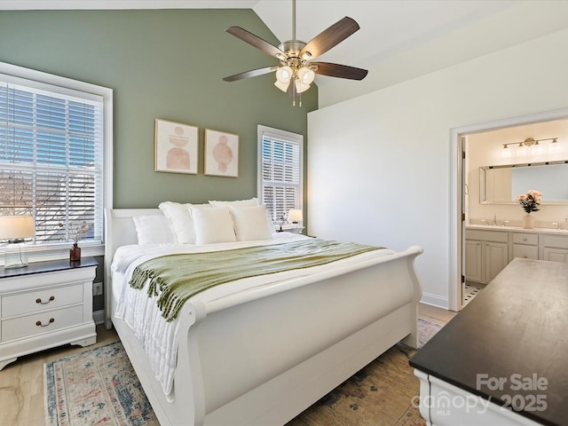 bedroom featuring vaulted ceiling, ensuite bath, sink, dark hardwood / wood-style flooring, and ceiling fan