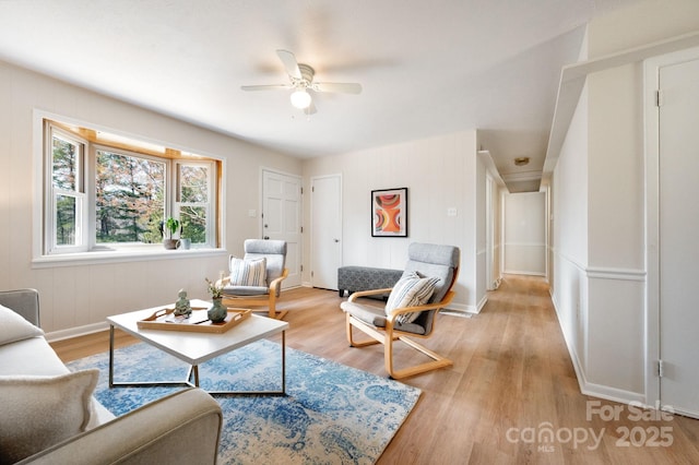 living area with baseboards, light wood-style floors, and ceiling fan