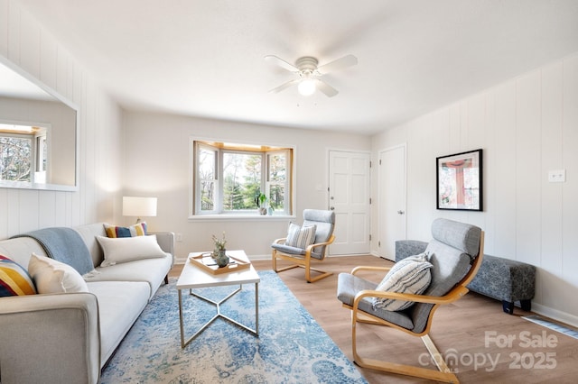living area with plenty of natural light, baseboards, light wood finished floors, and ceiling fan