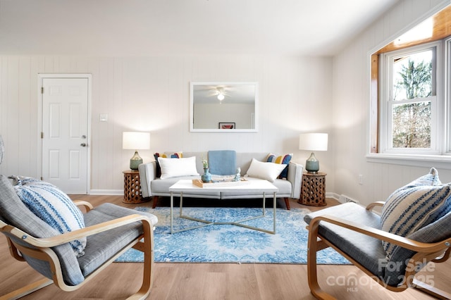 living room with baseboards, wood finished floors, and a ceiling fan