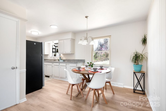 dining area featuring baseboards, visible vents, a chandelier, and light wood-style floors