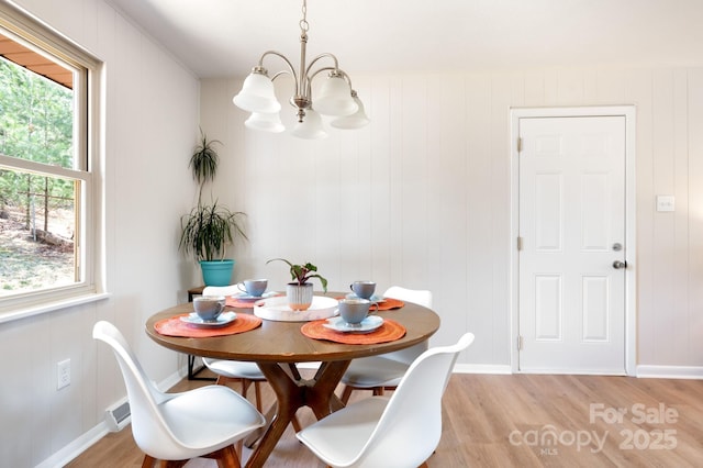 dining room featuring baseboards, visible vents, a chandelier, and light wood-style floors