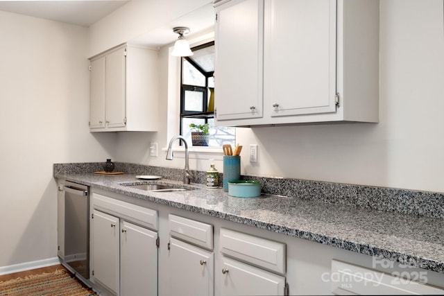 kitchen featuring white cabinetry, a sink, baseboards, and stainless steel dishwasher