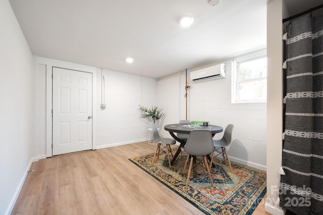 dining room featuring concrete block wall, a wall unit AC, baseboards, light wood-style floors, and recessed lighting