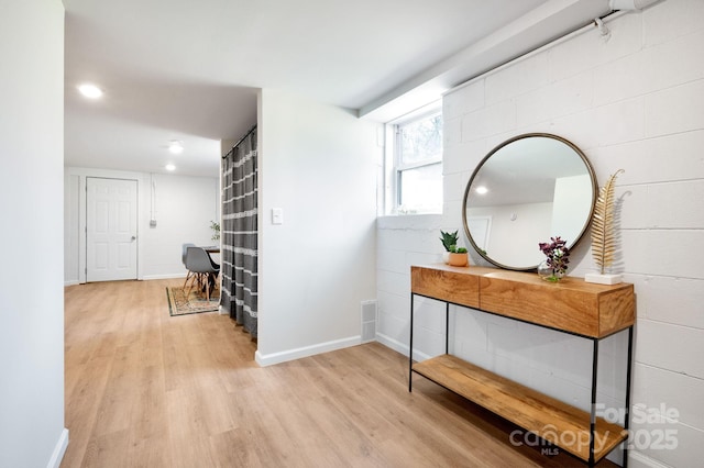 hall featuring baseboards, light wood-style flooring, and recessed lighting
