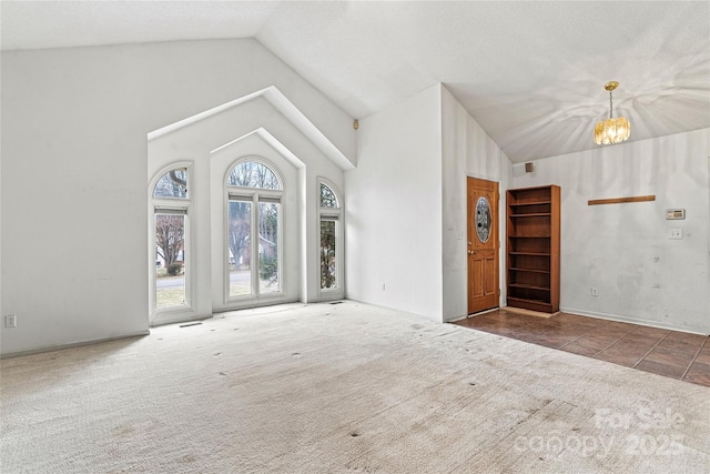 unfurnished living room featuring a chandelier, dark colored carpet, and high vaulted ceiling