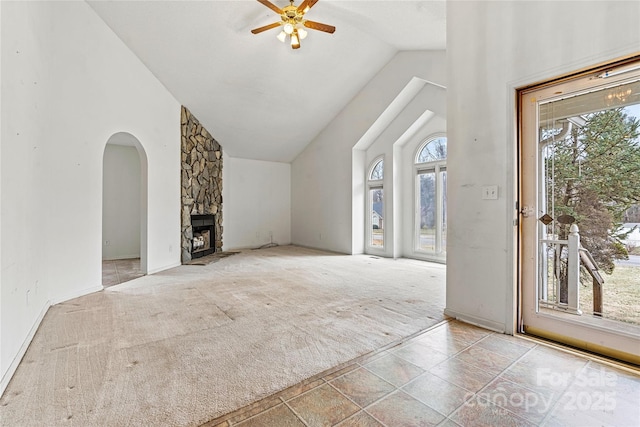 unfurnished living room featuring light carpet, ceiling fan, high vaulted ceiling, and a fireplace