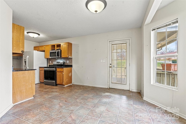 kitchen featuring backsplash, a textured ceiling, light tile patterned floors, and stainless steel appliances